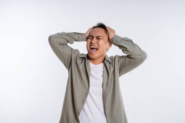 Genç bir adam ellerini stüdyoda başının üstüne koyarak hayal kırıklığı ve üzüntü gösterir.