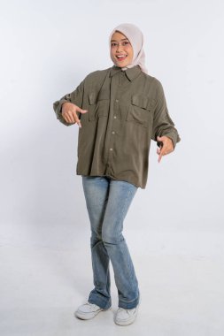 Genç bir kadın gündelik kıyafetlerle cazibe saçıyor, gülümsüyor ve açık havada poz veriyor.