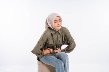 Başörtüsü takan bir kadın sandalyede otururken gözle görülür şekilde rahatsız olur.