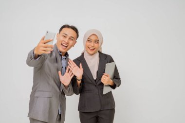 İki gülümseyen profesyonel ofis ortamında keyifli bir selfie çekiyorlar.