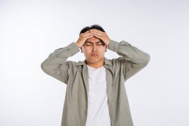 Genç bir adam kafasını derin bir hayal kırıklığı ve umutsuzluk içinde tutarken gözle görülür bir stres belirtileri gösterir.