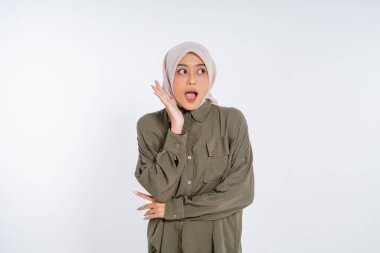 Şık tesettürlü genç bir kadın neşeli bir hareketle hoş bir sürpriz gösterir.