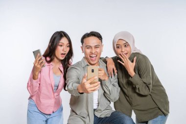 Üç arkadaş neşeli bir stüdyoda akıllı telefonlarıyla özel anları yakalıyorlar.