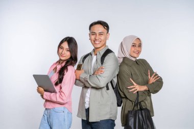 Üç genç profesyonel, teknolojik aletlerini ve aletlerini sergilerken özgüvenle poz veriyorlar.