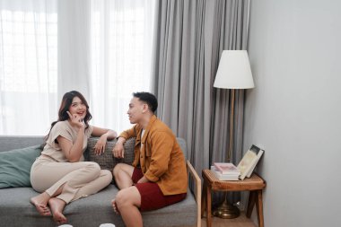 Genç bir çift şık, sıcak ve davetkar bir oturma odasında sohbet etmekten zevk alır.