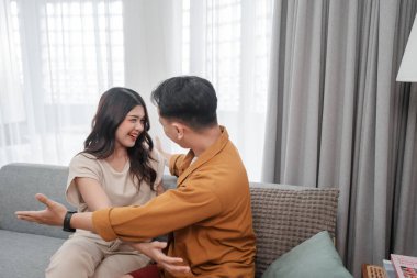 Neşeli bir çift, sıcak bir kanepede keyifli bir anı paylaşıyor, sevgilerini yayıyorlar.