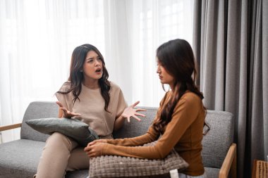 İki yakın arkadaş sıcak bir kanepede otururken samimi bir şekilde tartışıyorlar.