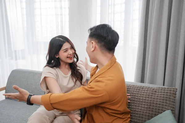 Neşeli bir çift, samimi ve davetkar bir oturma odasında birlikte kahkaha ve sıcaklık paylaşıyor.