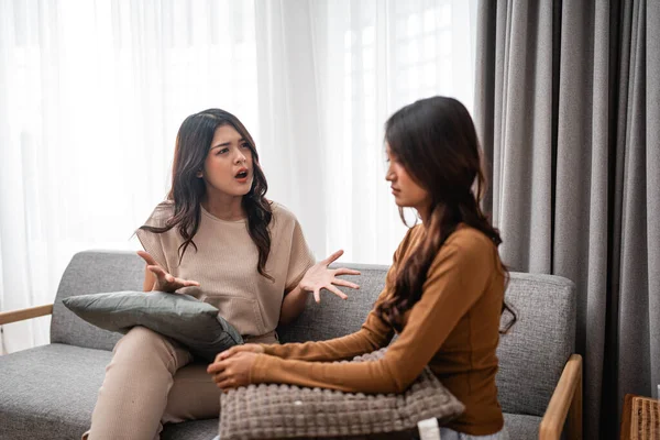 İki yakın arkadaş sıcak bir kanepede otururken samimi bir şekilde tartışıyorlar.