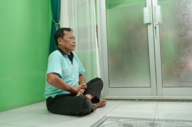 Bir adam güzel, yeşil bir odada huzur içinde oturuyor. Derin bir sükunet ve içgözlem simgeliyor.