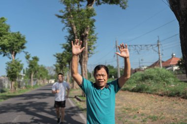 Neşeli bir adam, güzel yeşilliklerle çevrili, canlandırıcı doğa egzersizinin tadını çıkarır.