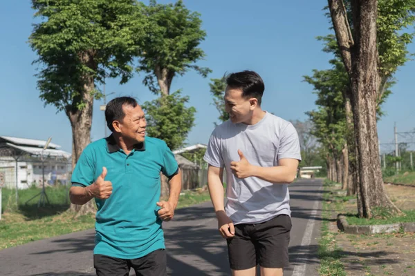 İki erkek birlikte dışarıda neşeyle yürüyorlar, fitness duygusunu ve derin dostluğu teşvik ediyorlar.
