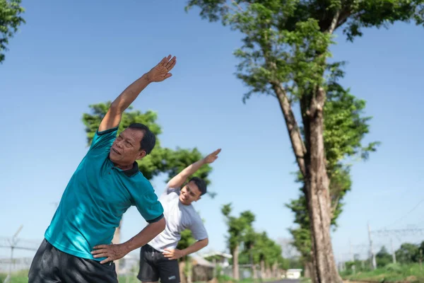 İki yaşlı adam sakin, sakin bir doğal ortamda esneme ve egzersiz yapıyorlar.