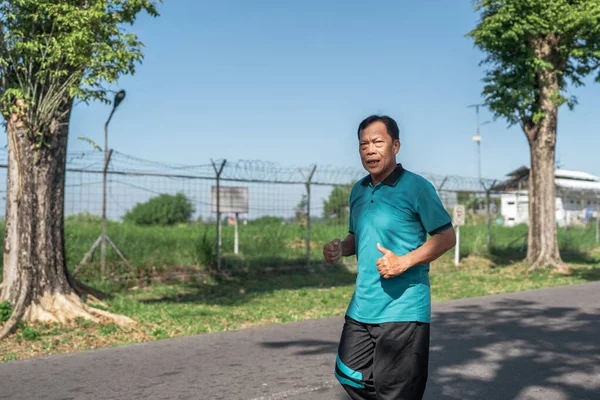 Yeşillik ve ağaçlarla çevrili güzel manzaralı bir yolda koşan bir adam.