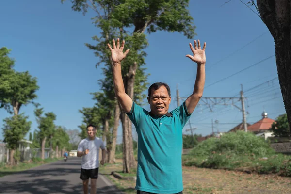 Kolları havada bir adam açık havada koşmaktan, neşeli ve aktif bir yaşam tarzını kucaklamaktan hoşlanır.