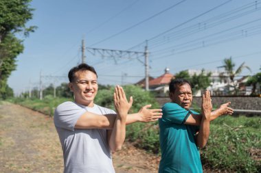 Bir grup erkek güneşli bir günde demiryolu hattının yanında egzersiz yapıyor.