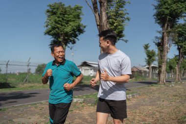 İki neşeli arkadaş güneşli bir parkta birlikte koşuyorlar, sağlık ve dostluğu destekliyorlar..