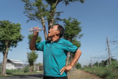 Güneşli bir egzersizden sonra, insan susuzluğunu gidermek için ferahlatıcı bir içkinin tadını çıkarır.