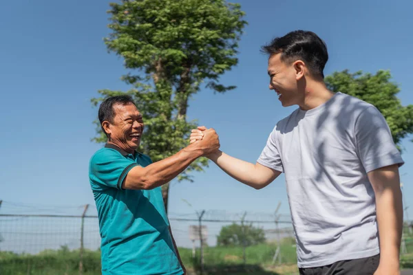 İki adam açık havada eğlenirken dostça bir bilek güreşi yapıyorlar.