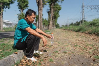 Düşünceli bir adam güneşli bir günde doğanın tadını çıkarırken demiryolu kenarında huzur içinde yatar.
