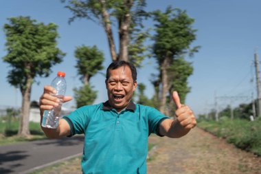 Neşeli ve mutlu bir adam açık havada güneşli bir günün tadını çıkarıyor.