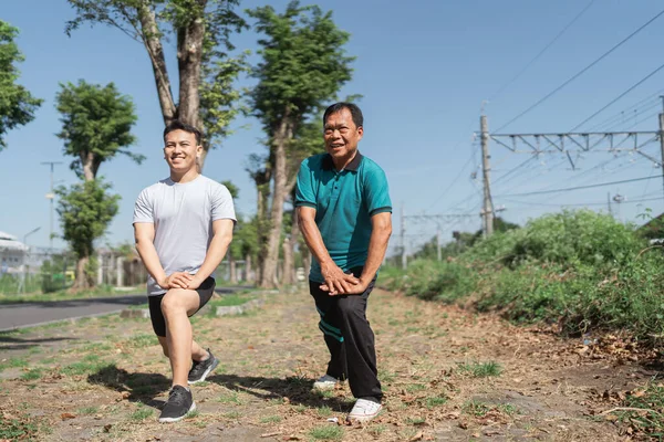 Erkekler, açık mavi gökyüzünün altında esneme de dahil olmak üzere, açık havada egzersiz rutinlerine hevesle dalarlar.