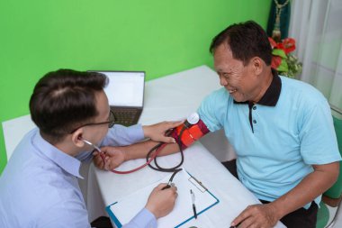 Tıbbi bir ortamda, bir tedarikçi hastaların tansiyonunu kontrol eder. Sağlık için bir monitörle.