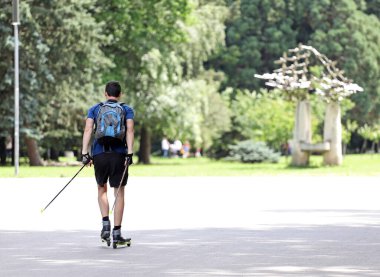 Adam parkta paten kayak yaparak kros yapıyor. Spor paten kayağı.