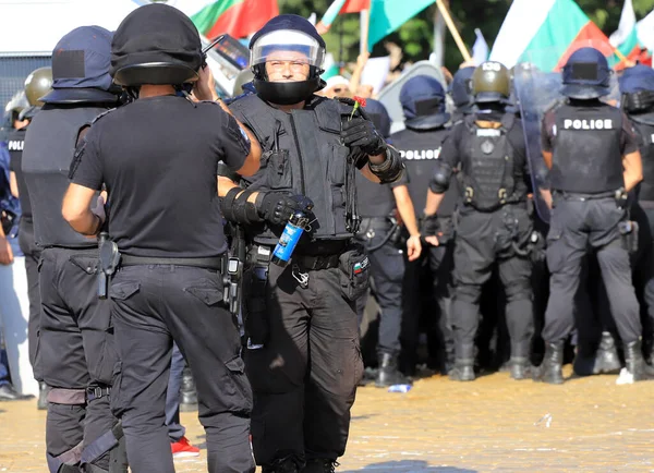 2 Eylül 2020 'de Bulgaristan' ın Sofya kenti: Ağır silahlı polis memurları, hükümet karşıtı protestoculardan biber gazı şişeleri ve çiçekler püskürtüyor