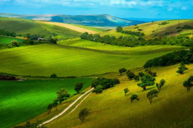 İngilizce kırsal, hills görüntü görüntü ortasında tepeler alt aracılığıyla çalışan bir kir parça ile her tarafında haddeleme tarım arazileri arazi küçük ağaçlar ve çalılar kırsal kenar otelde alanları Sussex İngiltere'de güzel tablomsu etkisi.