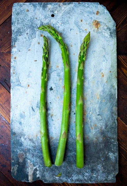 Three Stems Green Fresh Asparagus Rustic Grey Rectangular Stone Board — Stock Photo, Image