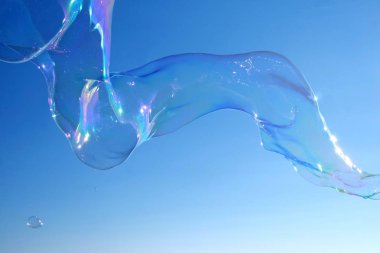 Brighton Plajı bir kabarcık değnek ile asa dan büyük büyük bir kabarcık duran bir kontrast adam gökyüzünde yüzen arkasında Brightons West Pier, gökyüzü arkasında parlak mavi, kabarcık şeffaf ama renkler yansıtan 