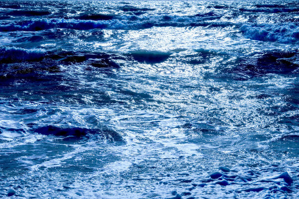 Темно-синее море с волнами набухает море имеет темные тени, где волны набухают и солнечный свет блестит белым на море на горизонтальном формате
