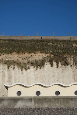 Cam kabinlerin her biri ile bir çakıl plajı bir beton duvar ile ve bir satır dört art deco tarzı Beach arkasında kulübeleri, plaj kulübe sit uçurumun üstündeki bir tebeşir uçurumun dibinde açık mavi gökyüzü, gökyüzü kopya için uygundur , Oving
