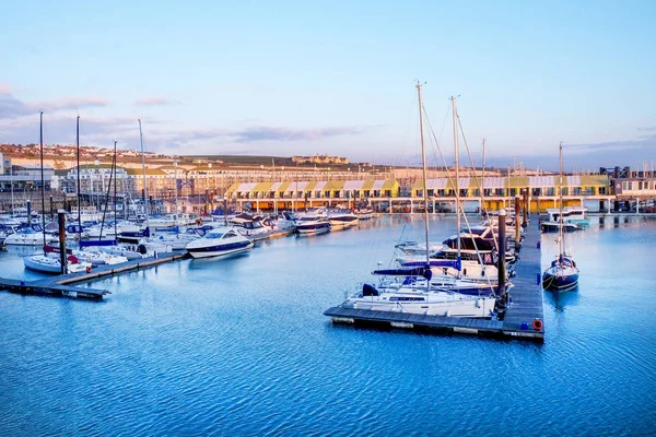 Brighton Marina, Sussex, Ingiltere, su üzerinde yüzen motorlu tekneler ve yelken tekneleri bir karışımı, arkasında ahşap Quays hatları karşı deniz limanı daireler ve dağ evleri vardır, arkasında binalar beyaz tebeşir kayalıkların ontop. 