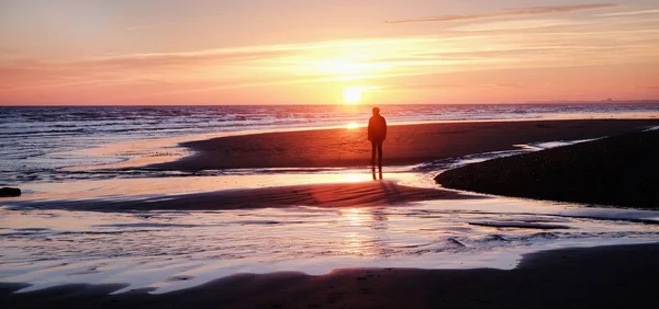 Homem irreconhecível andando em uma praia deserta ao pôr do sol — Fotografia de Stock