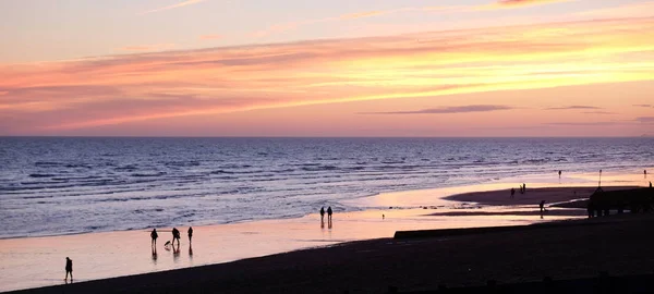 Unerkennbare Menschen gehen bei Sonnenuntergang am Strand von Brighton spazieren — Stockfoto