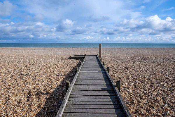 Długa prosta drewniana ścieżka na kamienistej plaży prowadzącej do morza — Zdjęcie stockowe