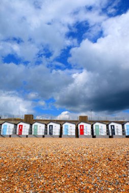 A line of beach huts on a pebble beach clipart