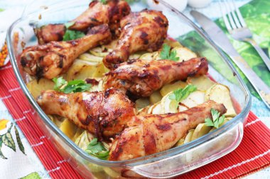 Patates ve kabak cam form ile pişmiş tavuk baget. Çatal, bıçak ve tuz ve biber kavanoz fotoğrafı vardır