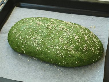 Ev yapımı ekmek nettles ile hazırlanması. Susam ile tepesinde bir fırın tepsisindeki yalan parşömen üzerine ekmektir