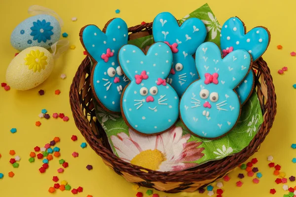 Easter funny rabbits, homemade painted gingerbread biscuits in glaze on a yellow background, top view