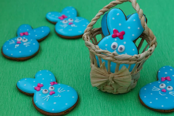 Easter funny rabbits, homemade painted gingerbread biscuits in glaze on a green background