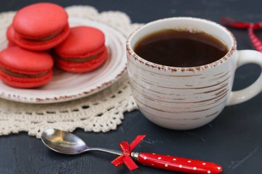 Bir fincan kahve koyu arka plan üzerinde macaroons mercan renk ile