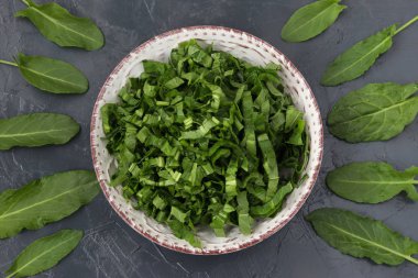 Kuzukulağı yaprakları keyfi olarak karanlık bir arka plan üzerinde yer alır, bir plaka ile dilimlenmiş kuzukulağı Merkezi'nden.