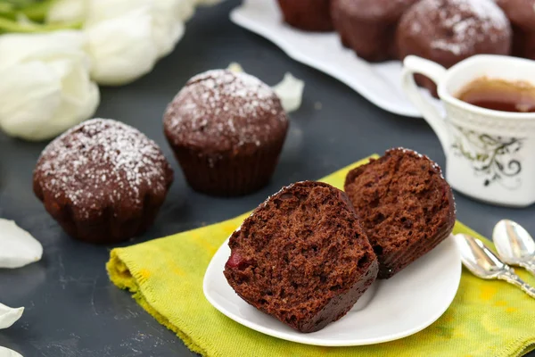 Suklaa muffinit kirsikka, peitetty jauhesokeria sijaitsee tummalla pohjalla — kuvapankkivalokuva