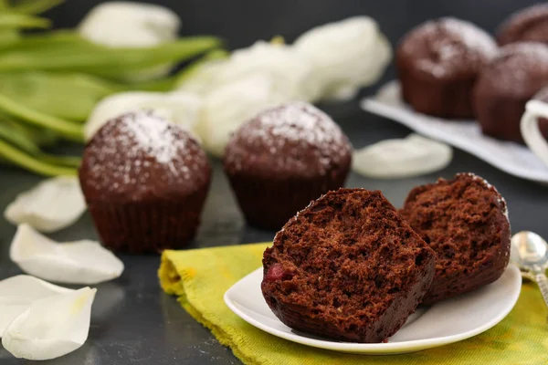 Шоколадные кексы с вишней, покрытые сахарной пудрой, расположенной на темном фоне — стоковое фото