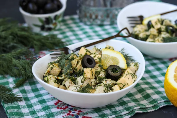Салат с курицей, сыром и черными оливками в белых мисках на столе — стоковое фото