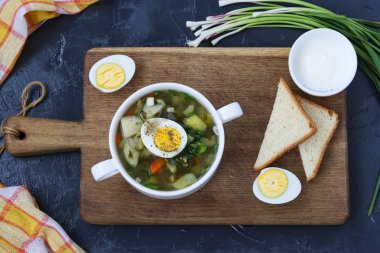 Bir ahşap tahta koyu arka plan üzerine beyaz tabaklar kuzukulağı ile yeşil borsch