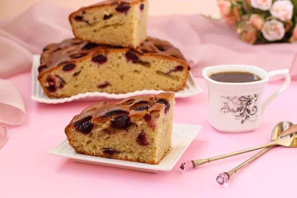 Пирог с вишней расположен на розовом фоне на тарелке, на столе чашка кофе и цветы — стоковое фото